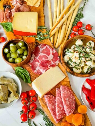 Closer top view of a Antipasti Italian Charcuterie Board on a white counter. Full of meat, cheese, olives, and more.