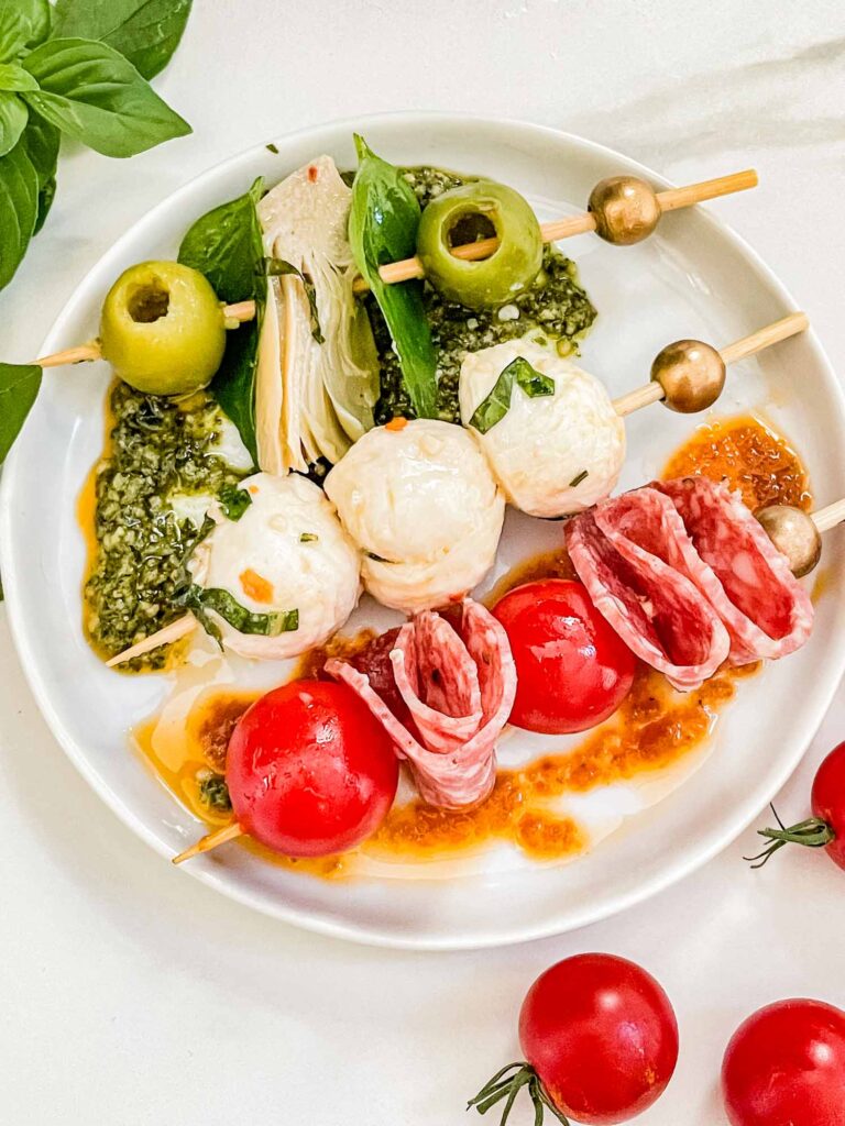 Skewers for Individual Italian Charcuterie Cups on a small white plate, laid out in green, white, and red rows.