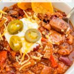 Pin of Smoked Brisket Chili Recipe in a bowl with title at top.