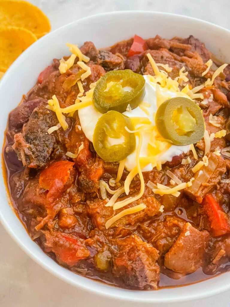 A bowl of Smoked Brisket Chili Recipe topped with sour cream and cheese.