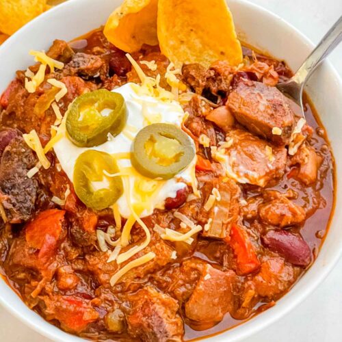 A white bowl full of Smoked Brisket Chili Recipe on a counter.