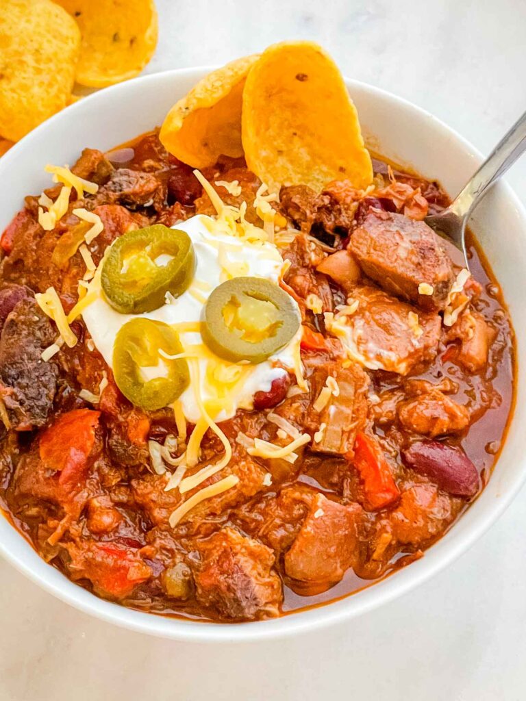 A white bowl full of Smoked Brisket Chili Recipe on a counter.