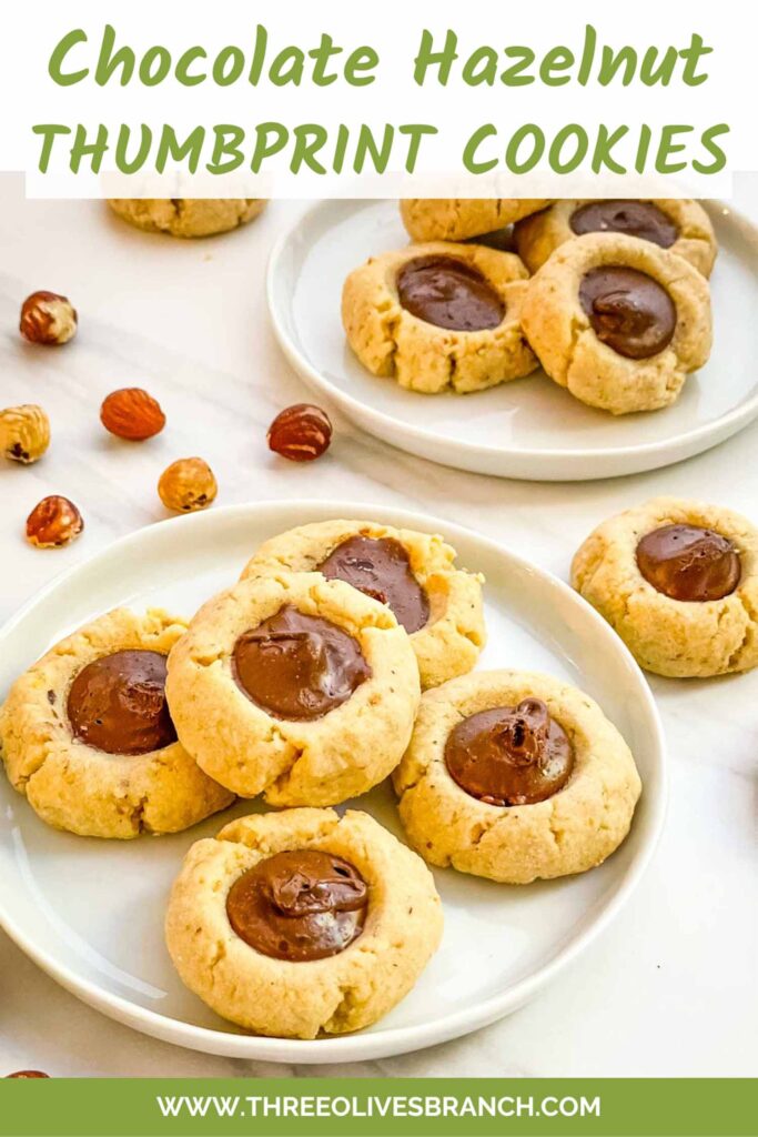 Pin of Chocolate Hazelnut Thumbprint Cookies on a small plate on a counter with title at top.