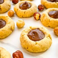 Closer view of Chocolate Hazelnut Thumbprint Cookies spread out on a white counter.