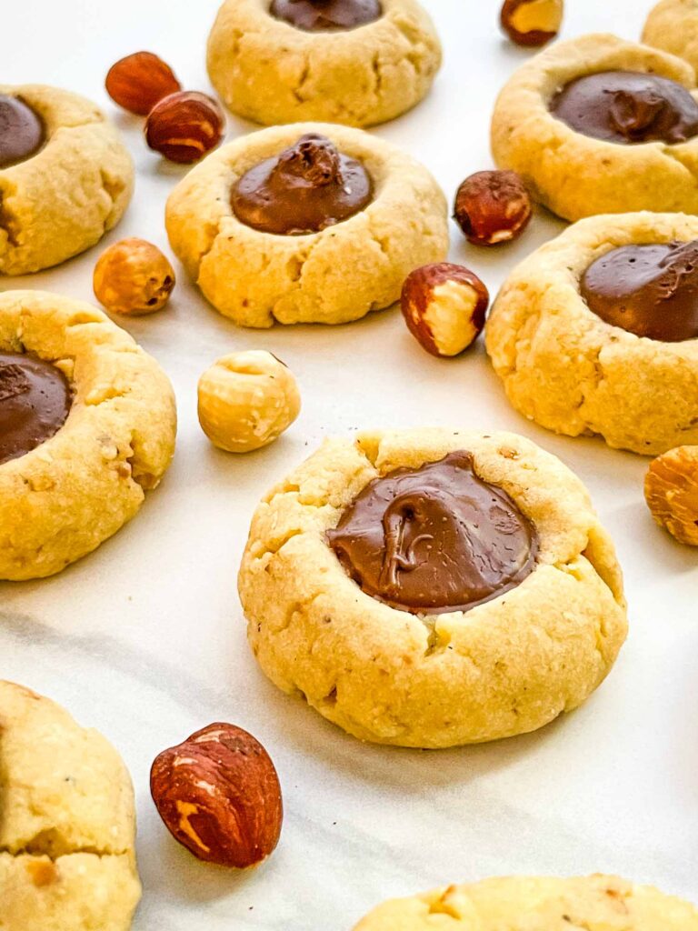 Closer view of Chocolate Hazelnut Thumbprint Cookies spread out on a white counter.