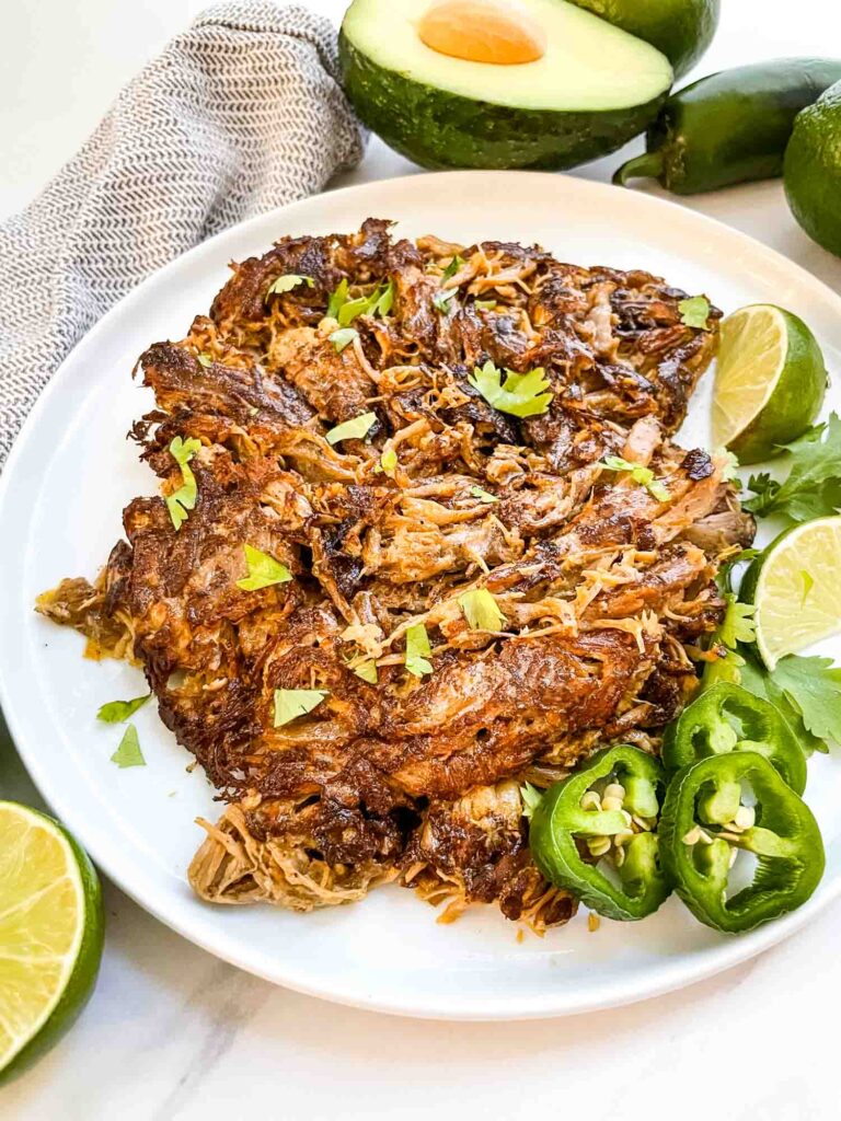 Seared Instant Pot Pork Carnitas on a white plate with jalapeno and cilantro.