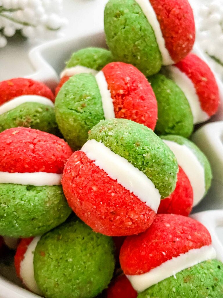 Close view of red and green Christmas Baci di Dama Cookies with white in the middle, in a pile.