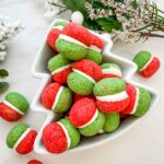 Red and green Christmas Baci di Dama Cookies in a tree shaped bowl on a counter.