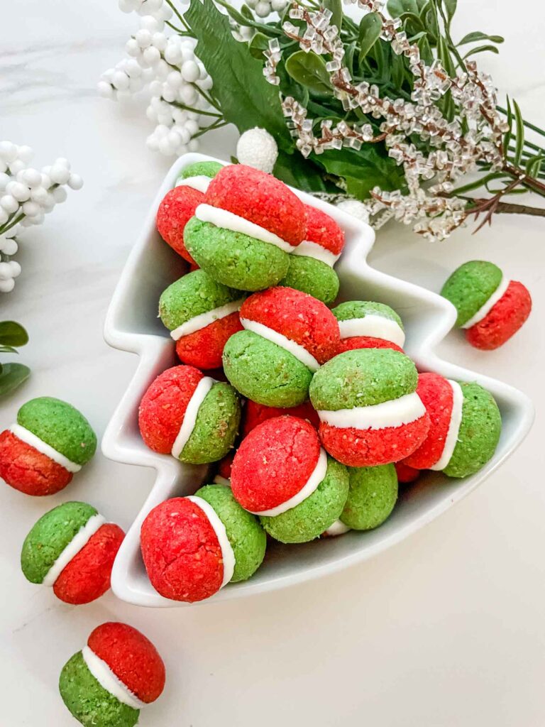 Red and green Christmas Baci di Dama Cookies in a tree shaped bowl on a counter.