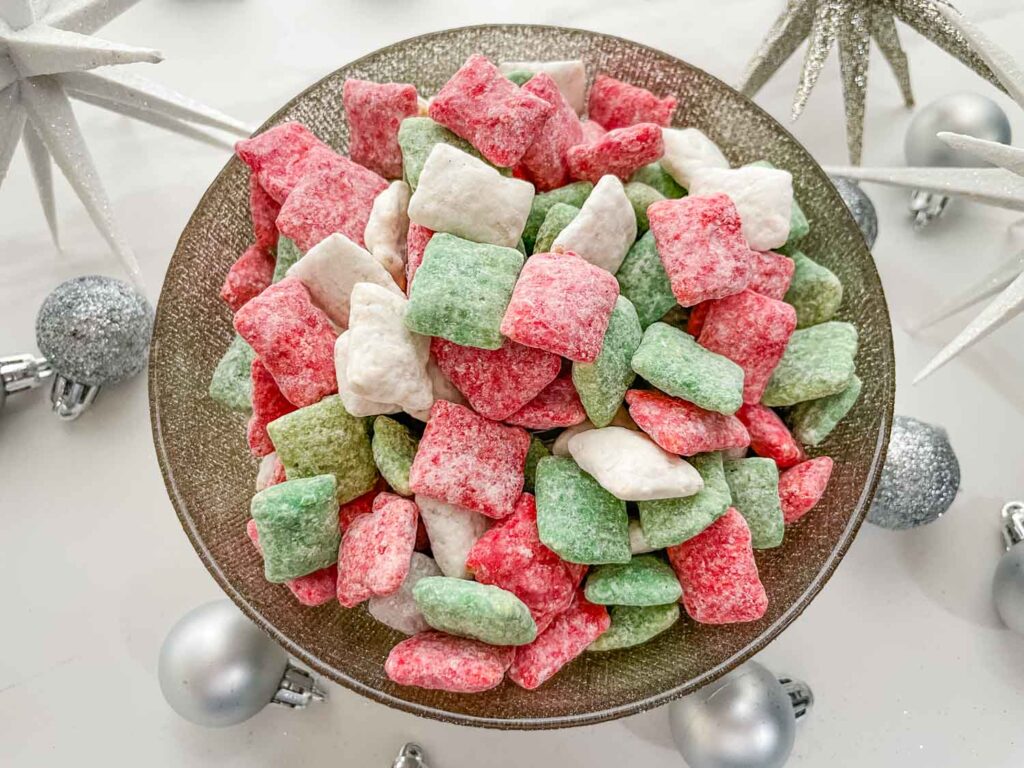 Looking down on a bowl of Holly Jolly Christmas Puppy Chow on a white counter.