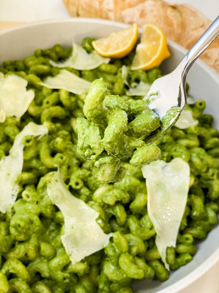 A fork lifting some Hazelnut Spinach Pesto Cavatappi out of the bowl.