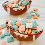 Two football bowls full of Miami Dolphins Puppy Chow on a white counter.
