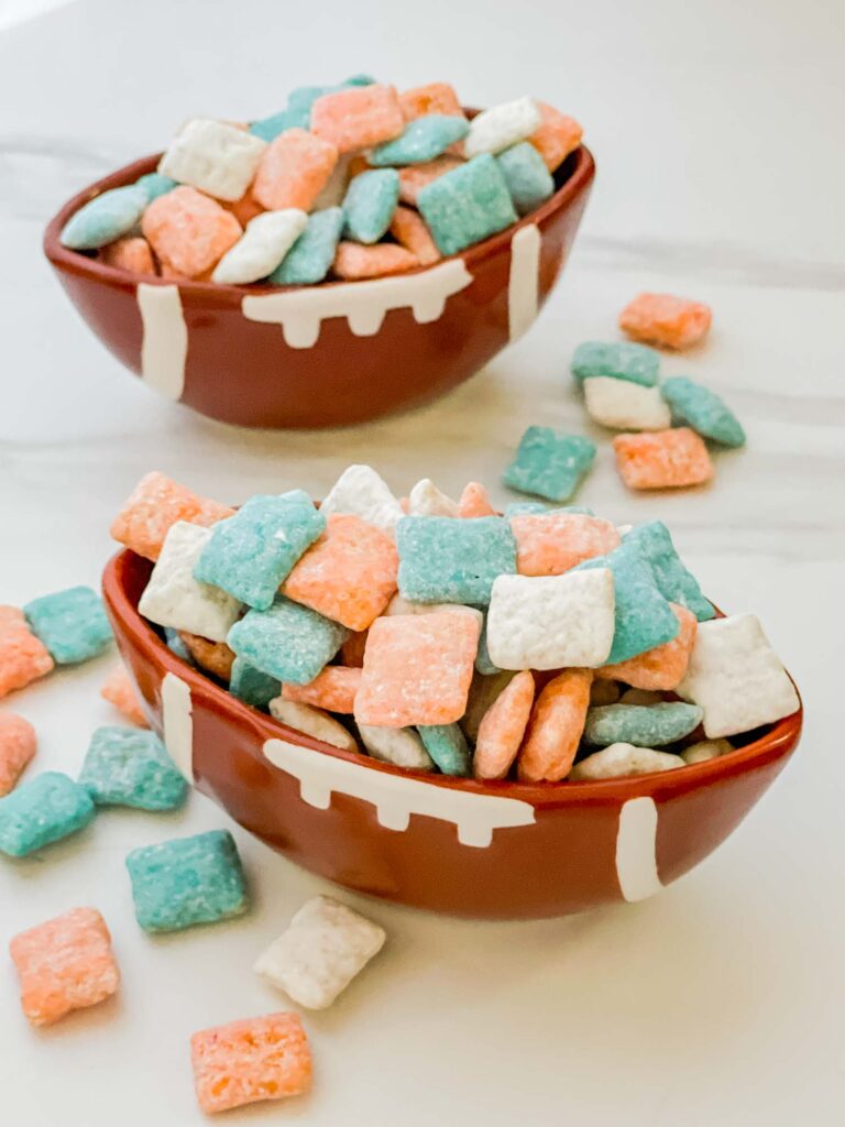 Two football bowls full of Miami Dolphins Puppy Chow on a white counter.