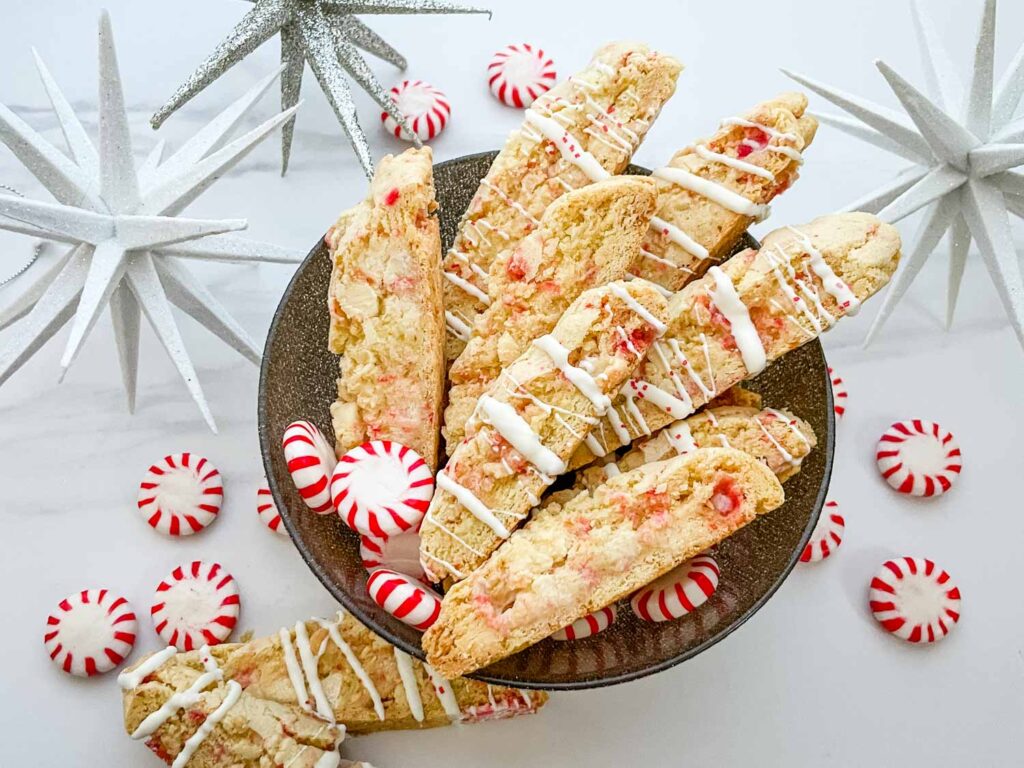 Looking down on White Chocolate Peppermint Biscotti cookies in a bowl sitting on a counter.