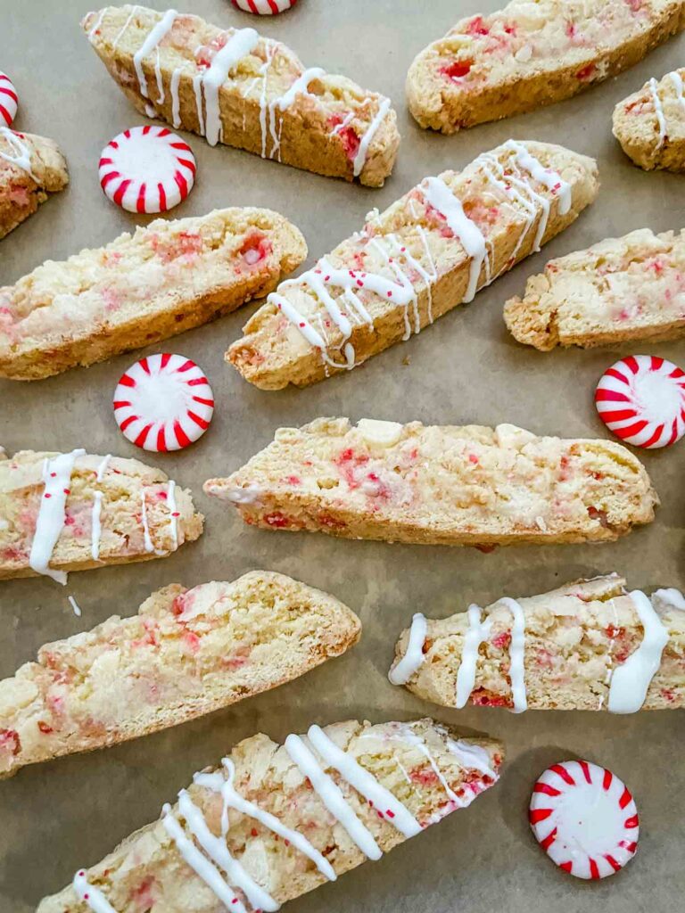 Slices of White Chocolate Peppermint Biscotti cookies scattered with some peppermints.