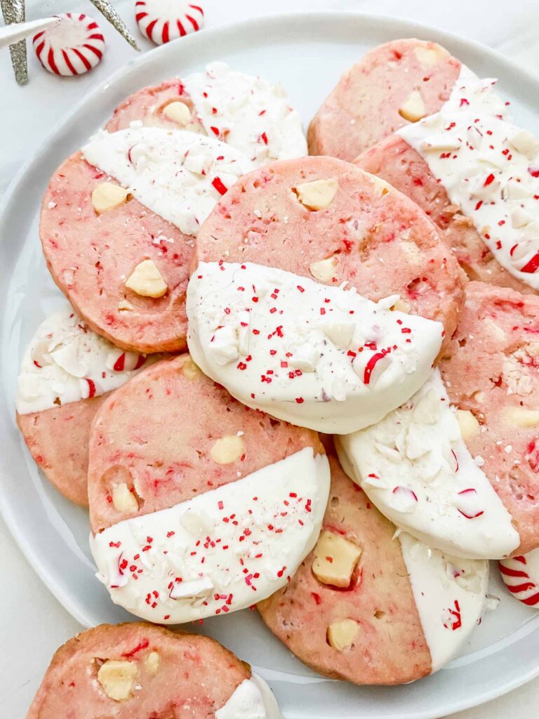 Closer view of pink White Chocolate Peppermint Shortbread cookies in a pile on a white plate.