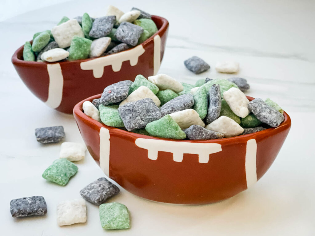 Two football bowls full of green, black, and white Philadelphia Eagles Puppy Chow.