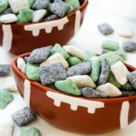 Two football bowls full of Philadelphia Eagles Puppy Chow in green, black, and white on a counter.