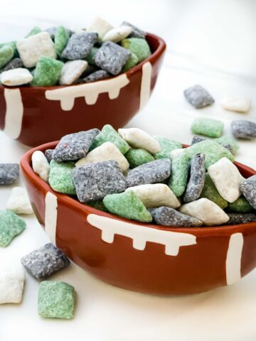 Two football bowls full of Philadelphia Eagles Puppy Chow in green, black, and white on a counter.