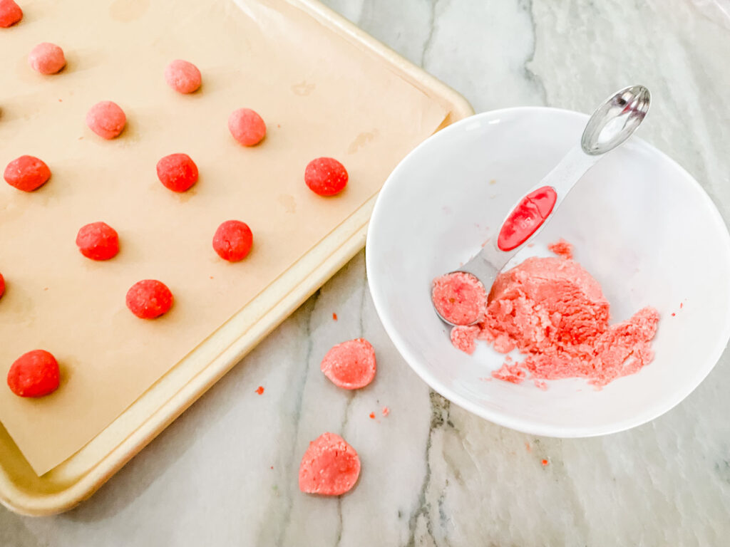 Pink and red dough being portioned and rolled.