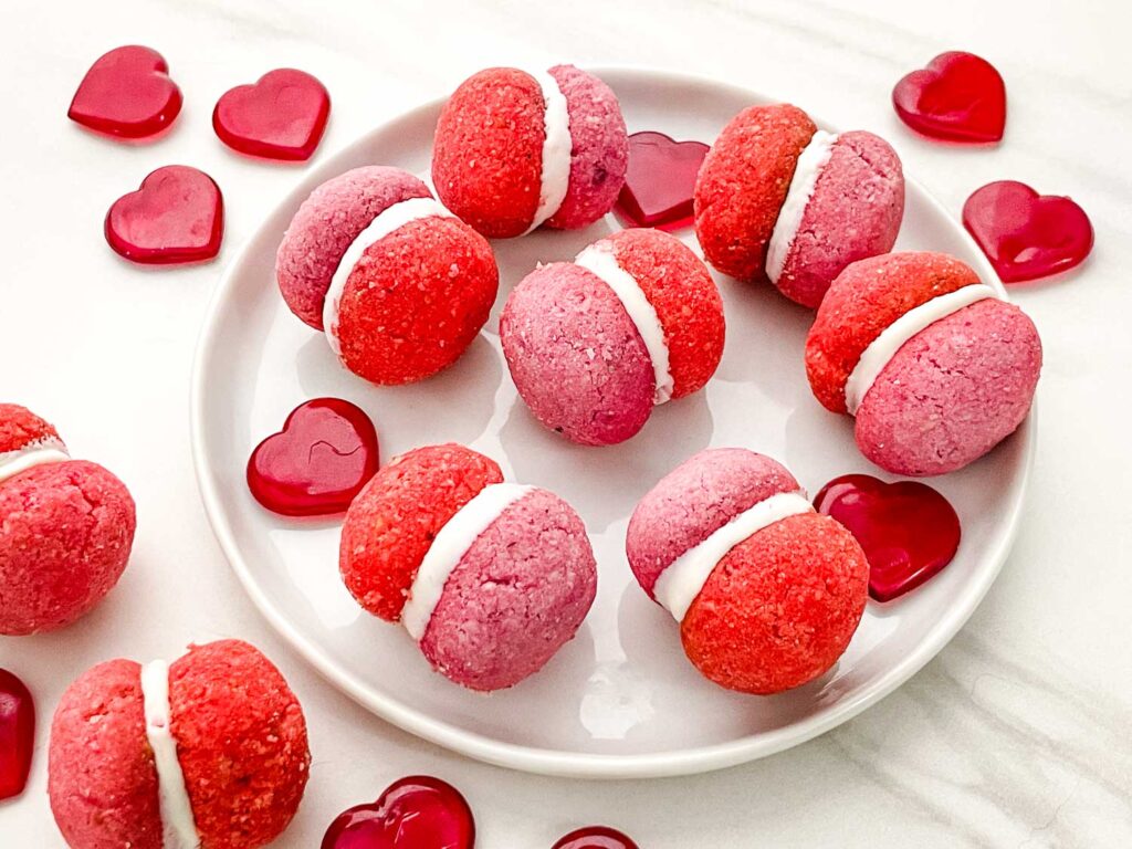 Pink and red Valentine's Day Baci di Dama Cookies on a small white plate.