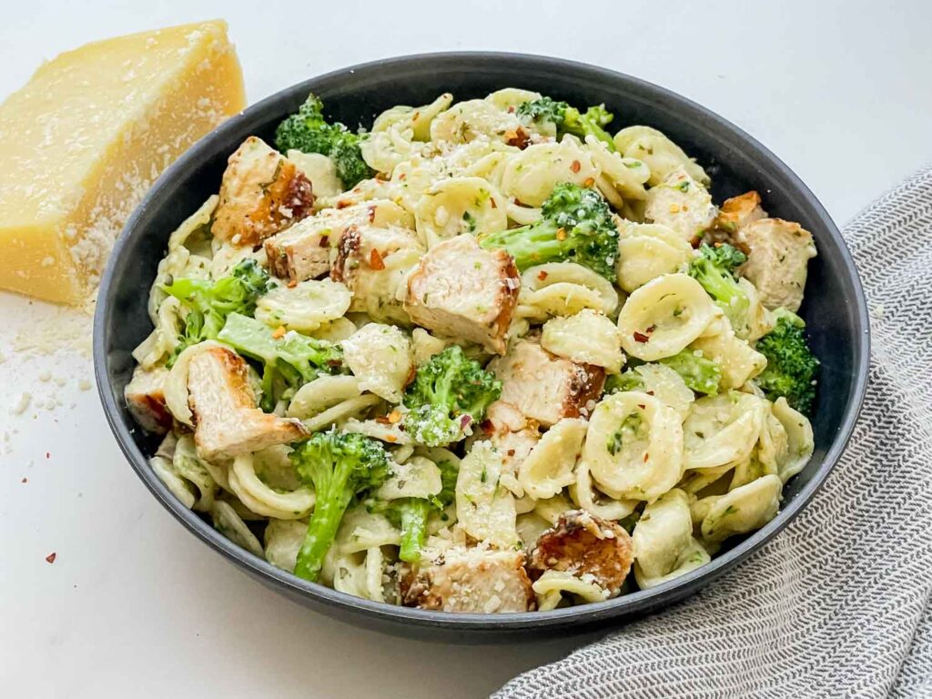 A dark bowl full of Copycat Olive Garden Chicken con Broccoli pasta sitting on a counter.