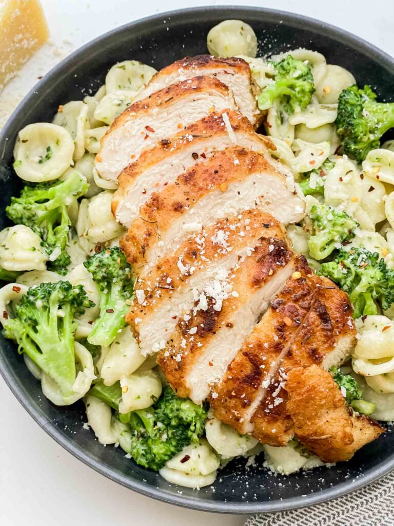 Top view of Copycat Olive Garden Chicken con Broccoli in a bowl with the chicken laying on top of the pasta.