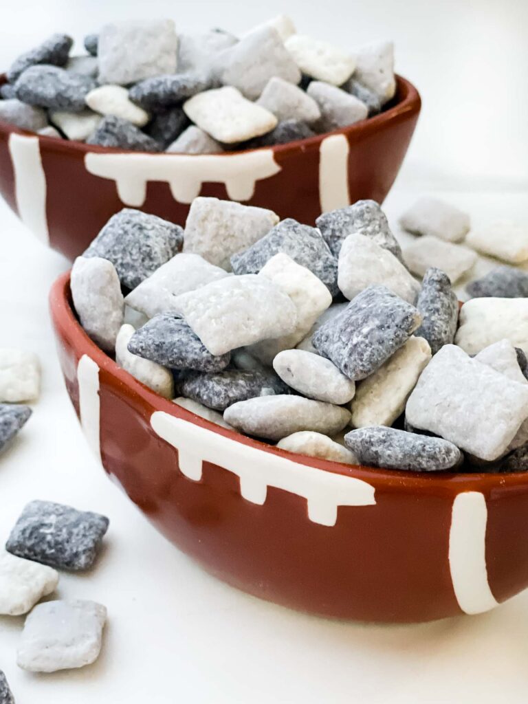 Two football bowls on a counter full of black, silver and white Las Vegas Raiders Puppy Chow.