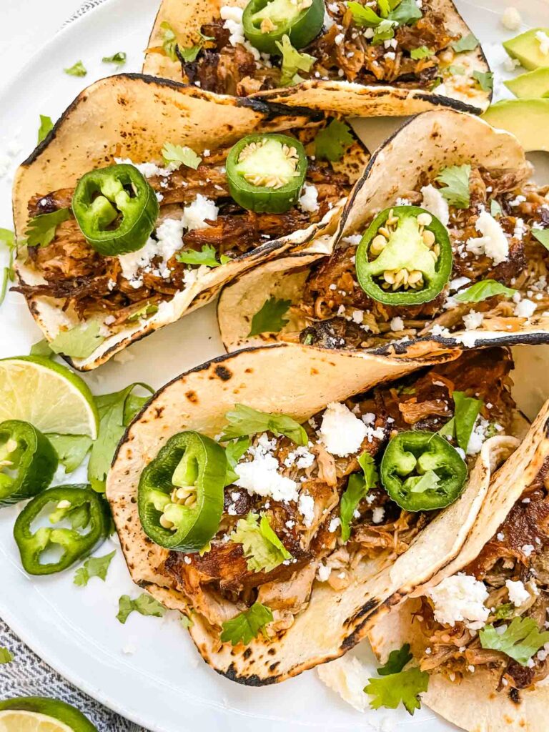 A closer view of Pulled Pork Carnitas Street Tacos stacked next to each other.