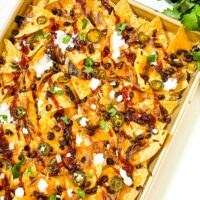 A baking sheet of Easy BBQ Pulled Pork Nachos Recipe on a counter.