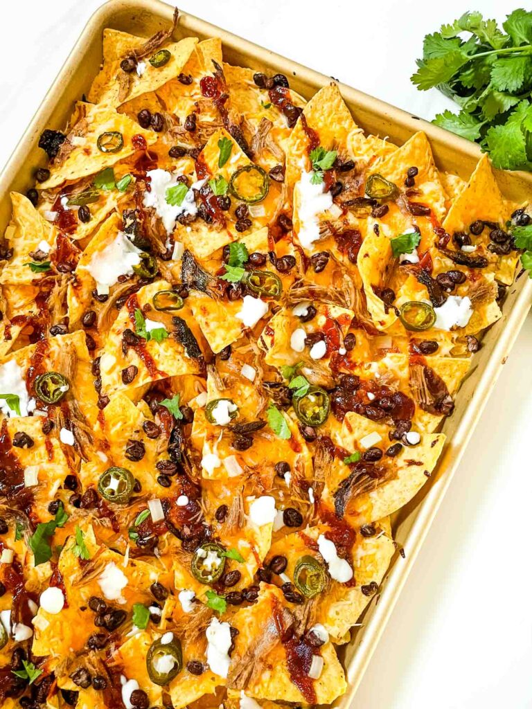 A baking sheet of Easy BBQ Pulled Pork Nachos Recipe on a counter.