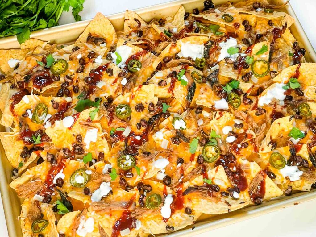 A tray full of Easy BBQ Pulled Pork Nachos Recipe on a counter.