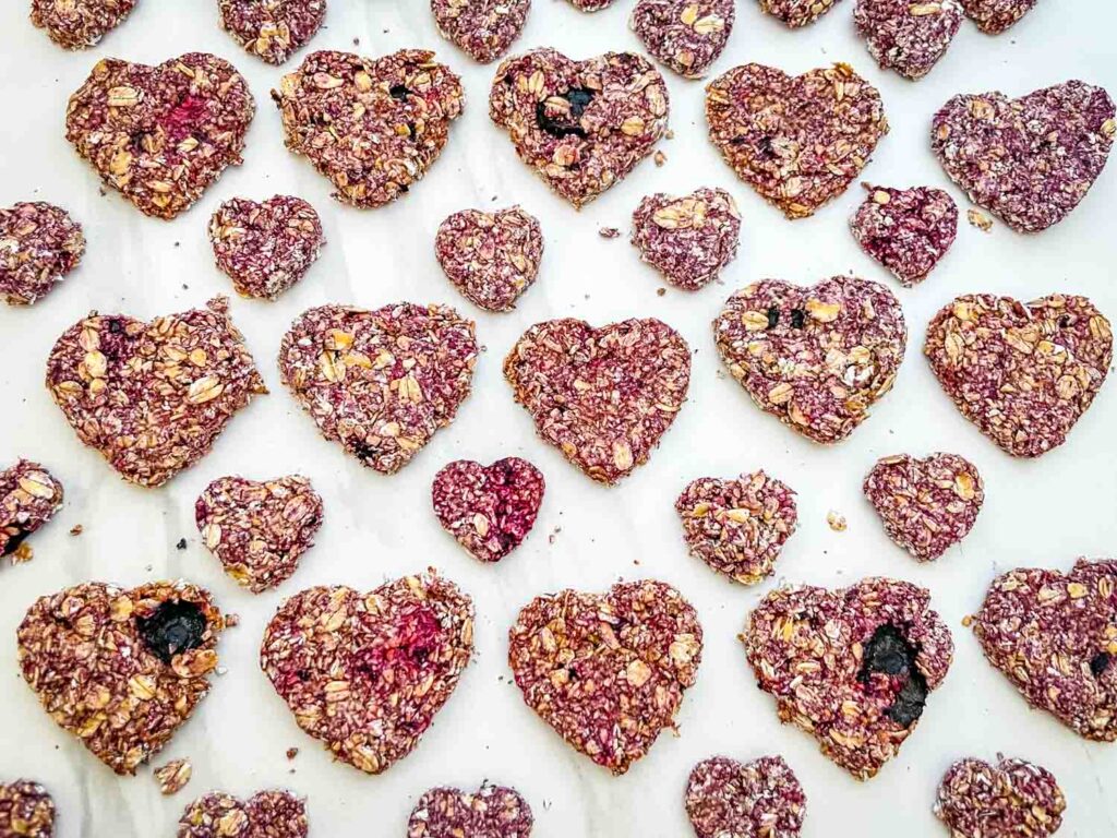 Rows of Crunchy Berry Parfait Dog Treats on a counter shaped like hearts.