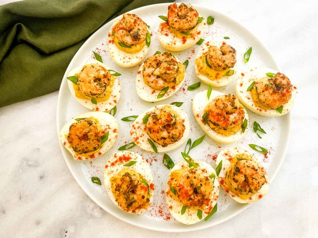 Looking down on a white plate of Cajun Shrimp Deviled Eggs on a counter.