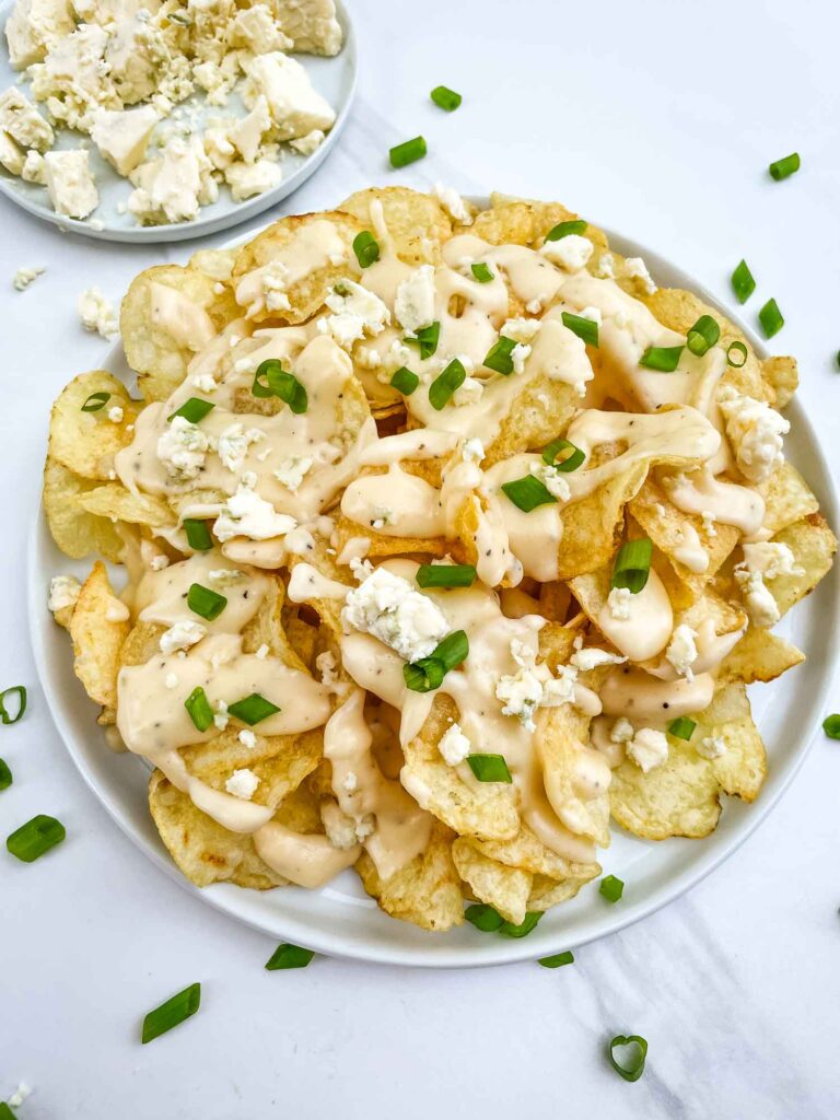 Looking down on a plate of Copycat Bennigan's Blue Cheese Chips on a white table.