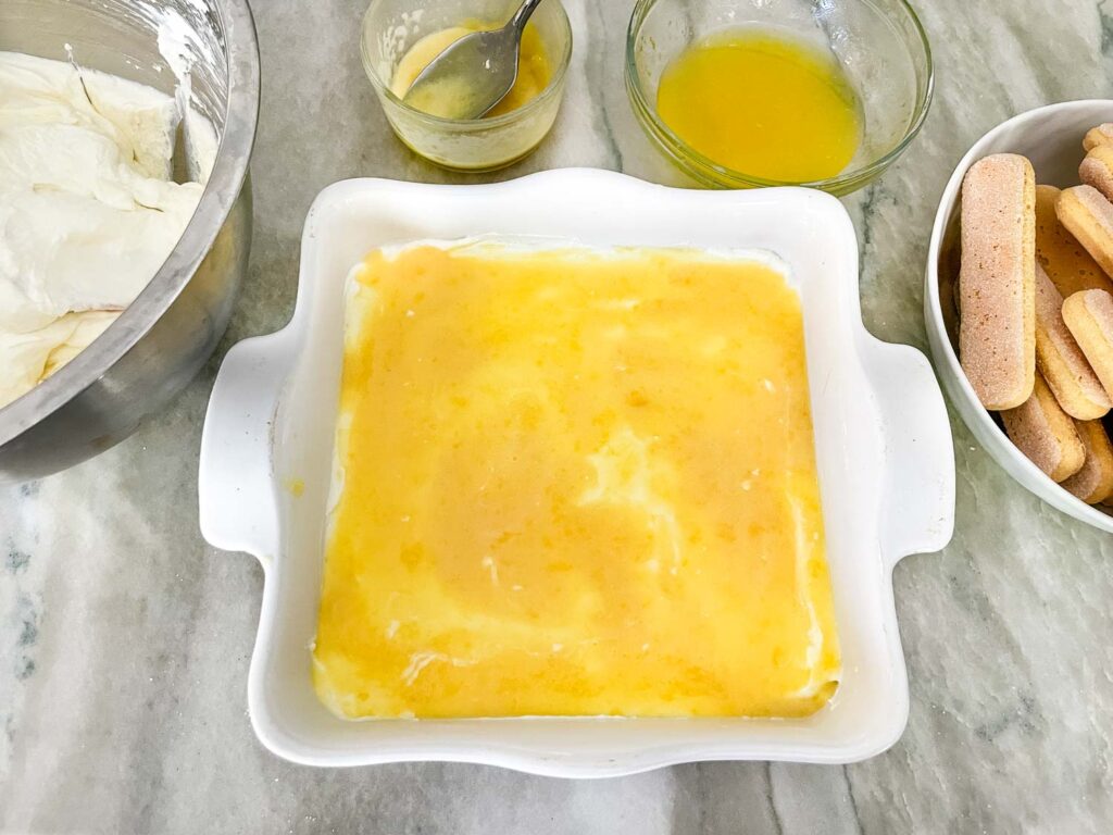 The first layer of cream and curd added to the square dish.