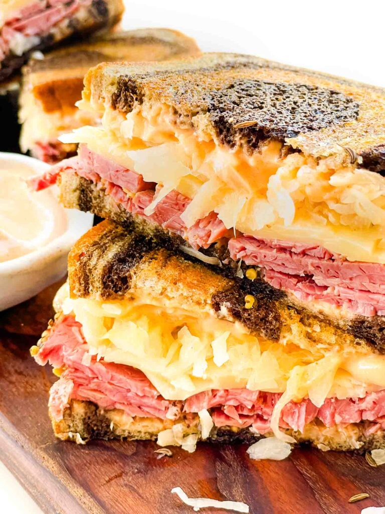 Close view of two Pastrami Reuben Sandwich halves stacked on top of each other.
