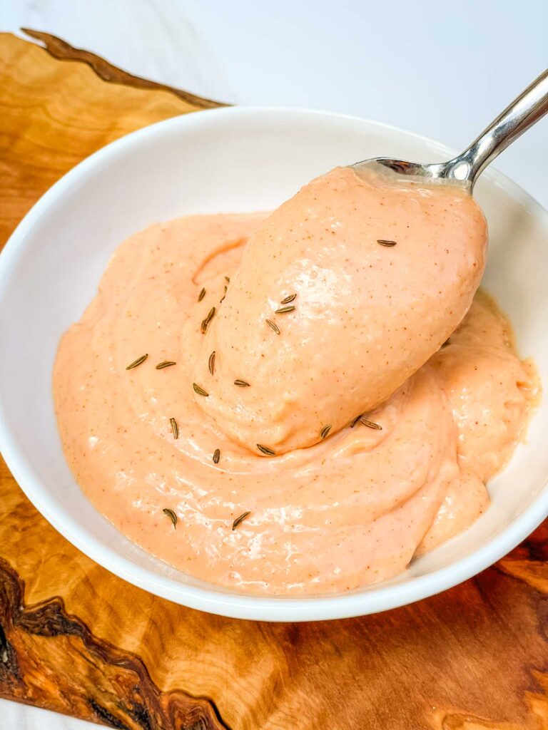A spoon scooping some Russian Dressing out of a bowl.