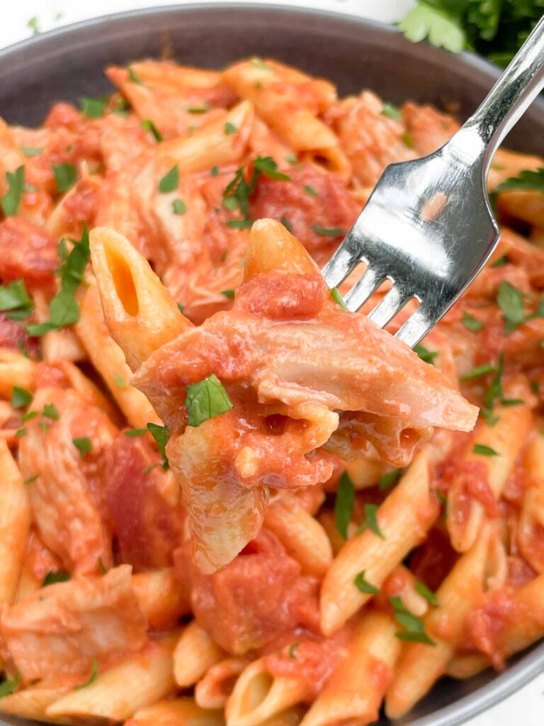 A fork with pasta and chicken on it above a bowl of the Chicken alla Vodka Pasta.