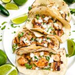 Looking down on four Chicken Street Tacos on a plate surrounded by limes.