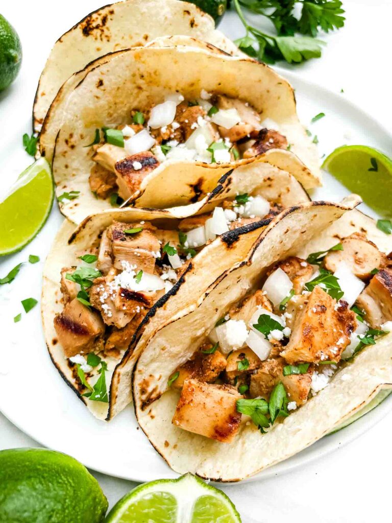Four Chicken Street Tacos in corn tortillas on a white plate.