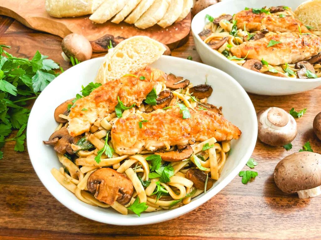 A bowl full of Copycat Olive Garden Chicken Marsala Fettuccine pasta on a table.