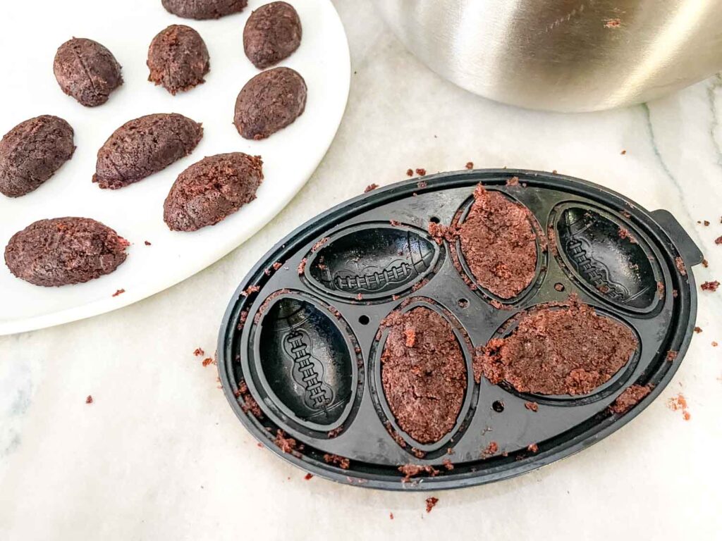 The cake mix being pressed into the football molds.