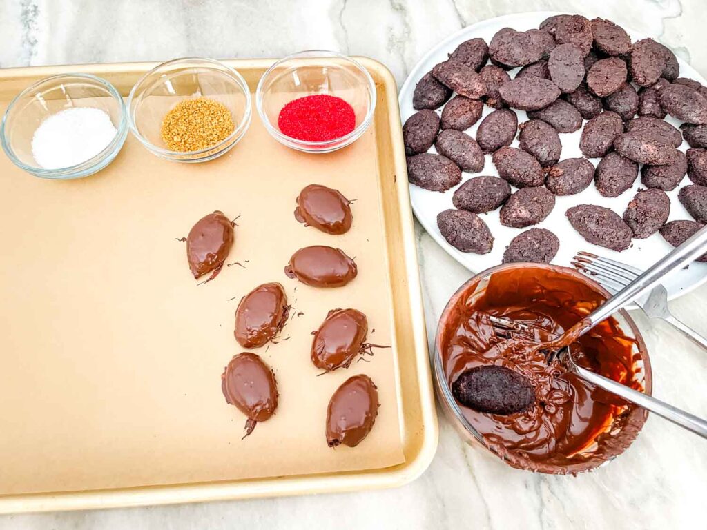 Football cake pieces in the process of being coated with chocolate and decorated.