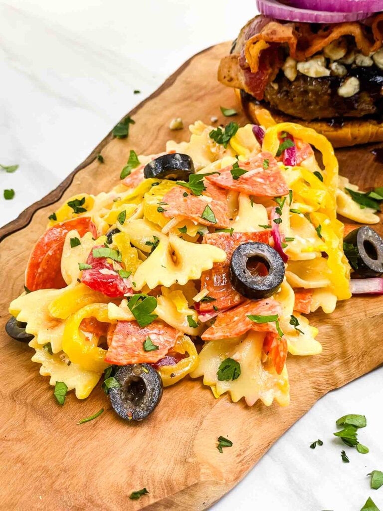 A pile of the Italian Pasta Salad with Pepperoni recipe on a wood board.