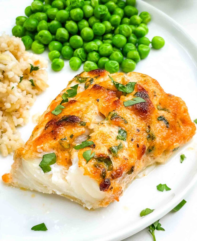 A full piece of Parmesan Baked Cod fish on a white plate.