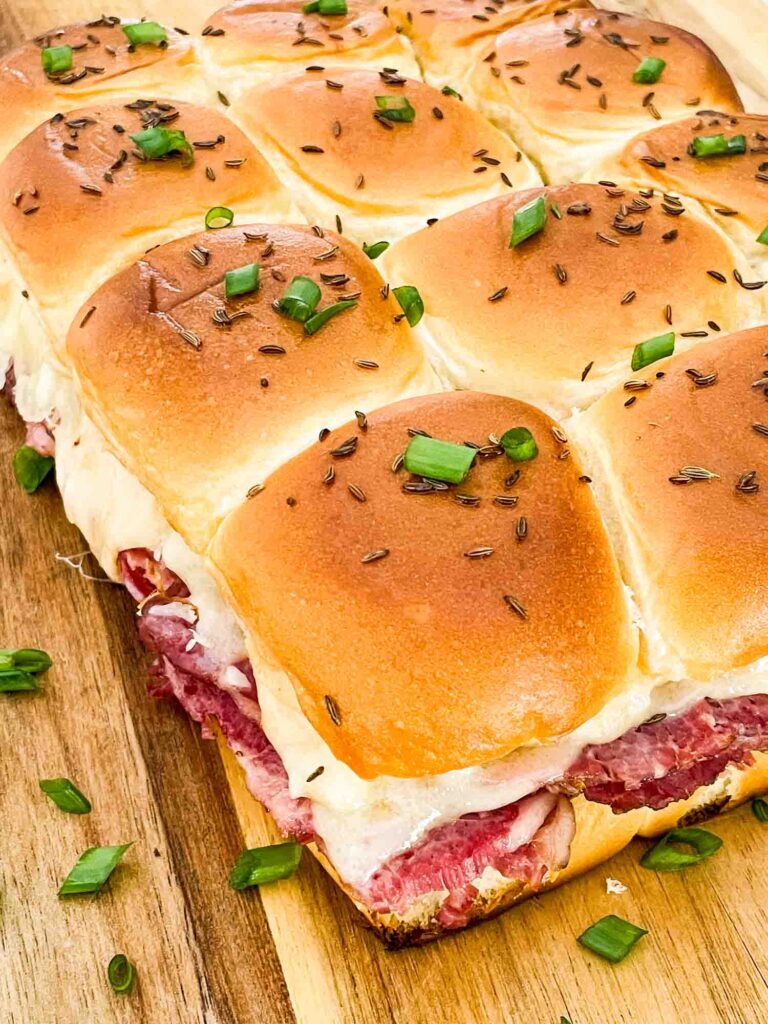 Looking down on the Corned Beef Reuben Sliders all stuck together and on a cutting board.
