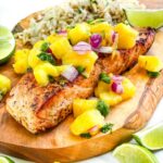 A filet of Salmon with Mango Salsa on a wood board.