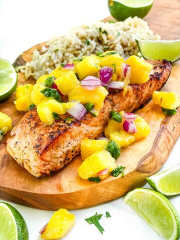 A filet of Salmon with Mango Salsa on a wood board.