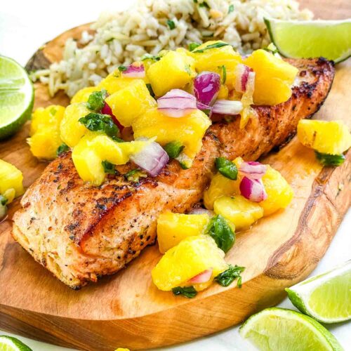 A filet of Salmon with Mango Salsa on a wood board.